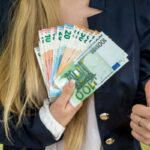 donna con il pollice rivolto verso l'alto e tante banconote in una mano