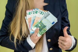 donna con il pollice rivolto verso l'alto e tante banconote in una mano