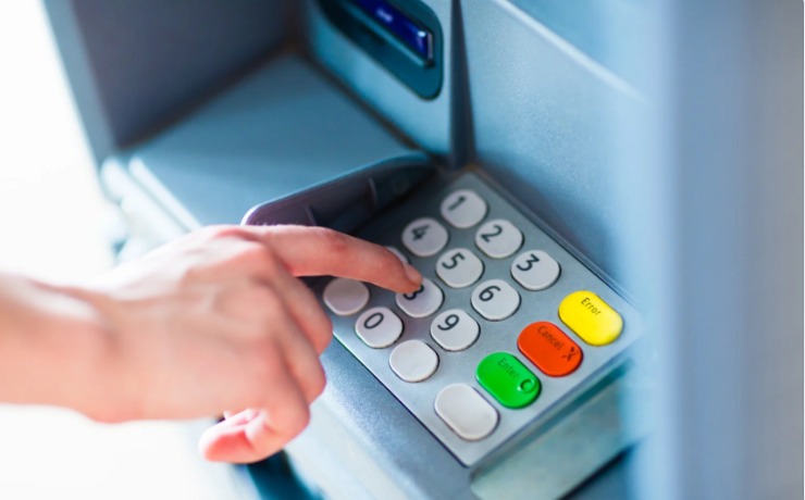 persona che preme dei tasti sulla tastiera del bancomat