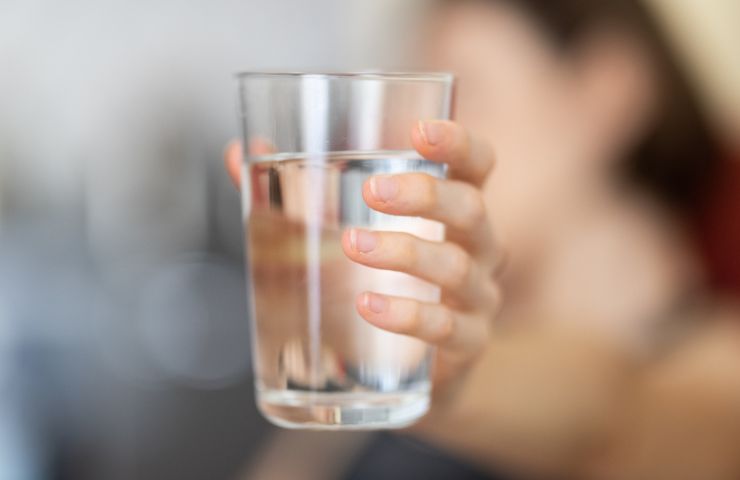 donna che tiene in mano bicchiere di acqua splendent