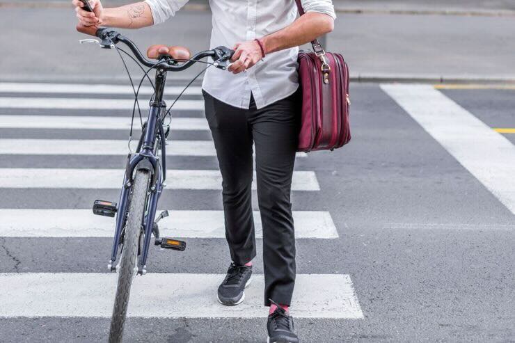 Ragazzo conduce a mano bici su strisce pedonali