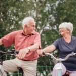 uomo e donna anziani in bicicletta che sorridono