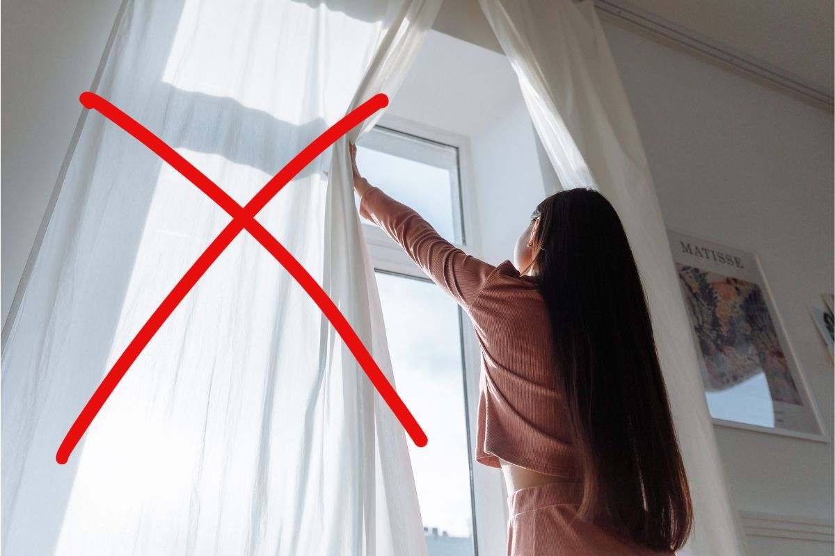 una persona che sta aprendo le tende di casa e una X sopra