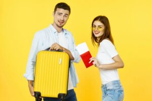 ragazzo che solleva un trolley e ragazza con in mano un passaporto